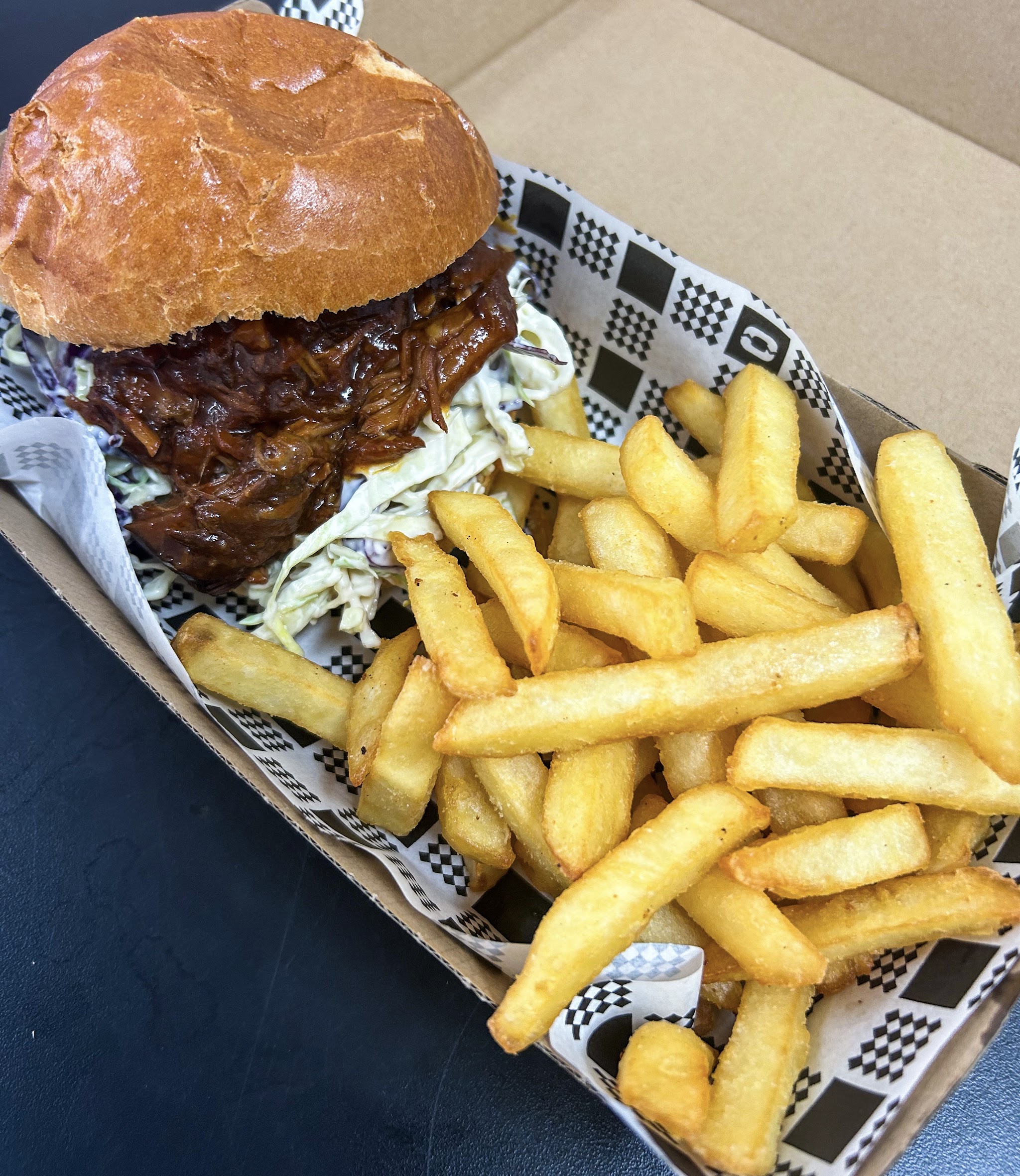Pulled pork burger with slaw and chips in a takeaway tray